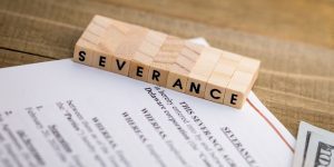 severance spelled out in blocks on top of an severance agreement document